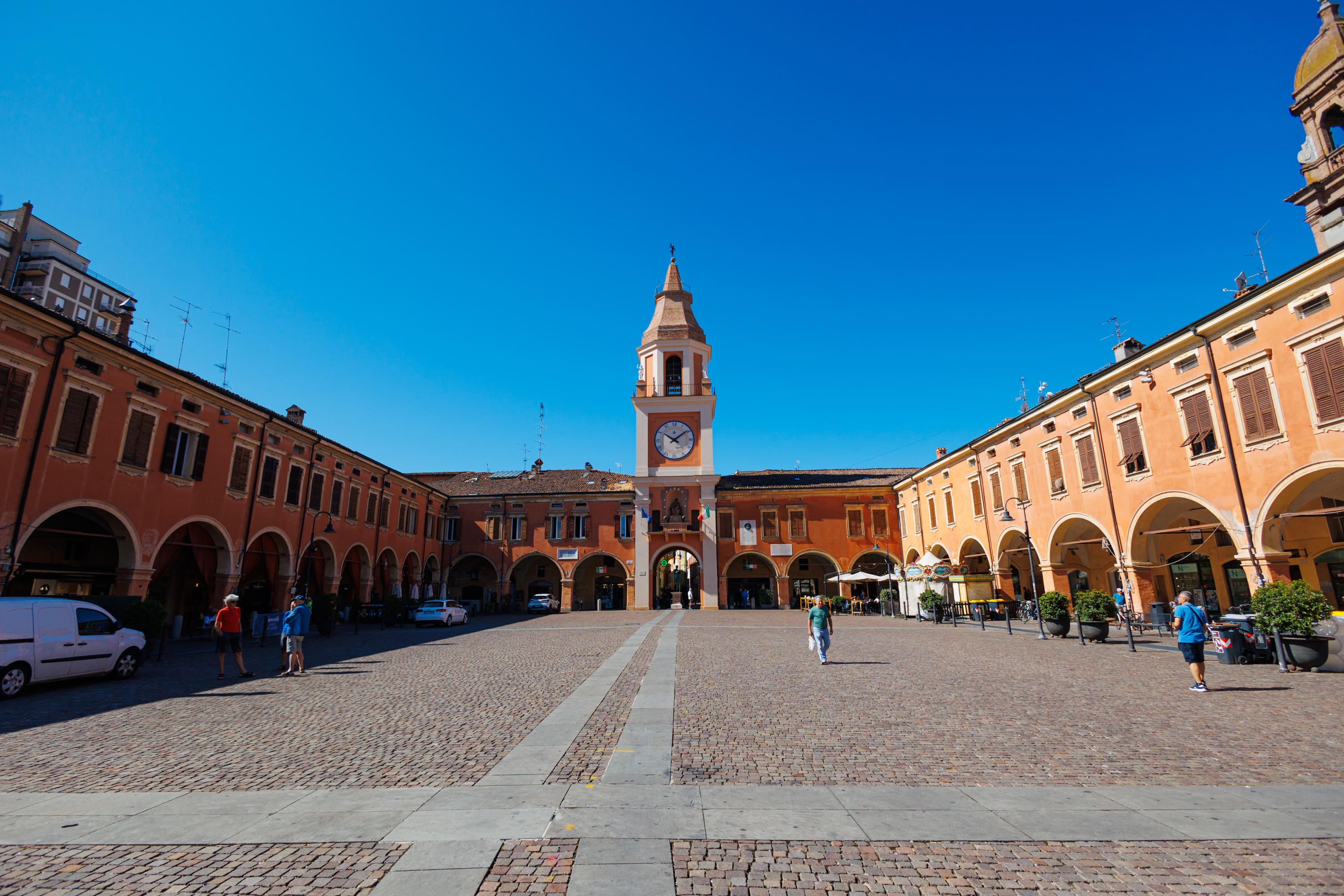 Piazza centrale di Sassuolo con la Torre dell’Orologio e i portici storici in una giornata di sole.